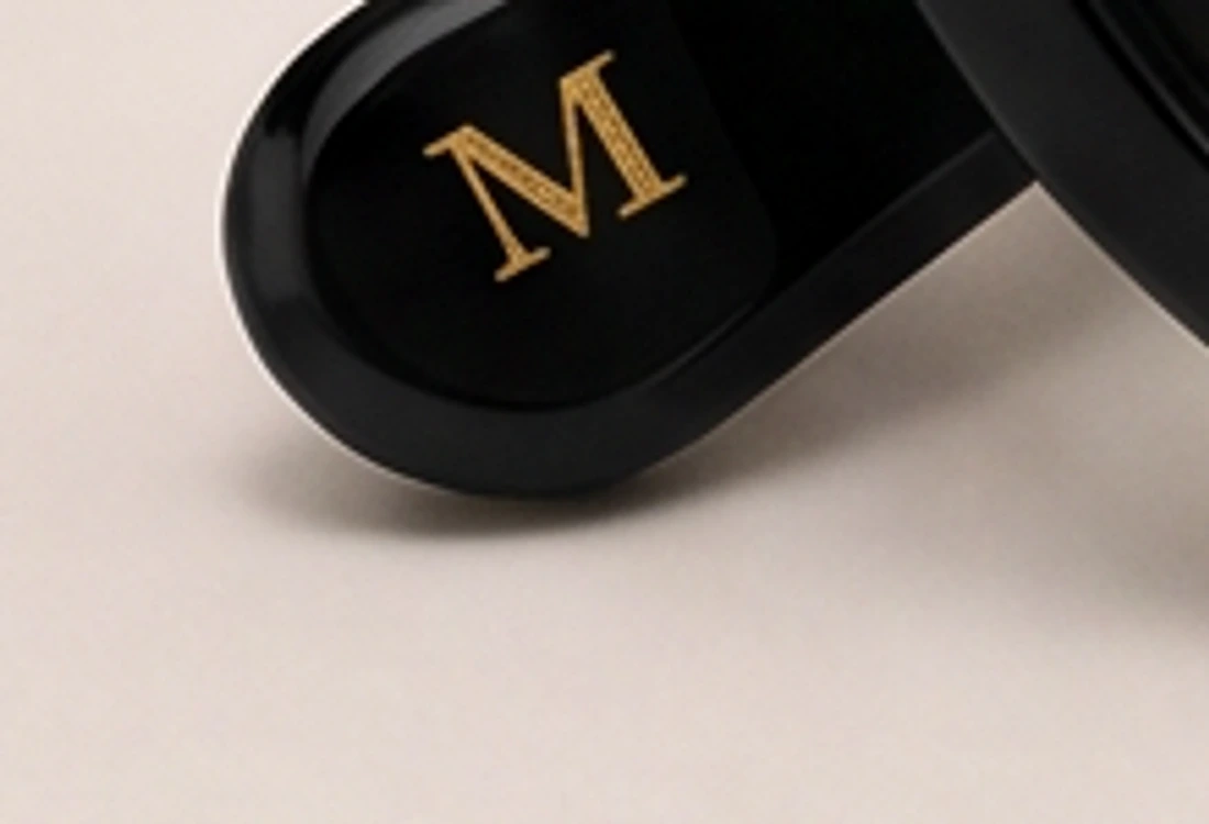 Macro detail of the temple tip, gold M mark on black acetate